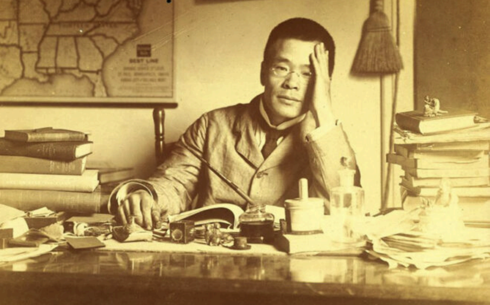 Ritratto fotografico d’epoca di D.T. Suzuki seduto alla scrivania, circondato da libri e carte